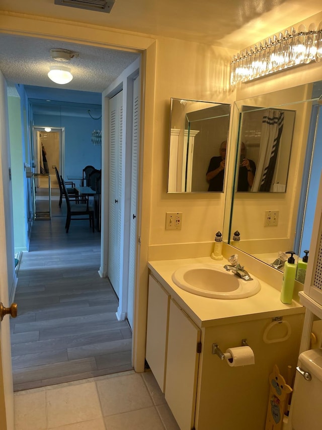 bathroom with vanity, hardwood / wood-style flooring, toilet, and a textured ceiling