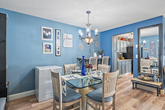 dining area with a notable chandelier, a textured ceiling, and light hardwood / wood-style flooring