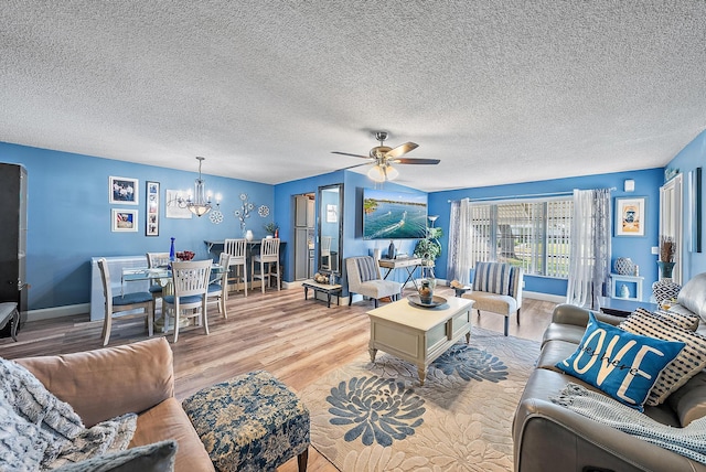 living room with wood-type flooring, ceiling fan with notable chandelier, and a textured ceiling