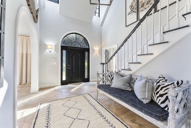 foyer entrance with a towering ceiling and light parquet flooring