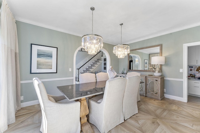 dining area with light parquet floors, ornamental molding, and a notable chandelier