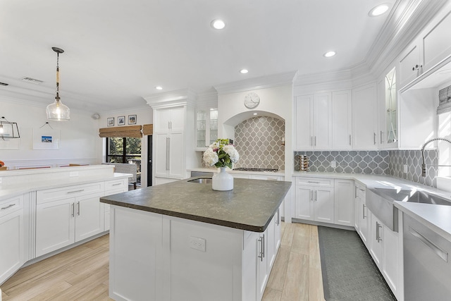 kitchen with appliances with stainless steel finishes, decorative light fixtures, white cabinetry, sink, and a center island