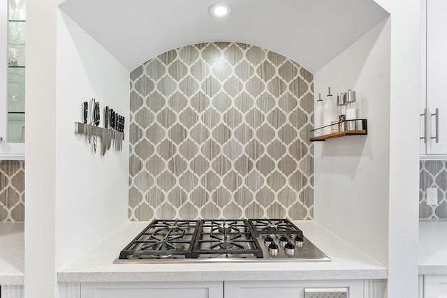 kitchen featuring stainless steel gas stovetop, white cabinetry, and decorative backsplash