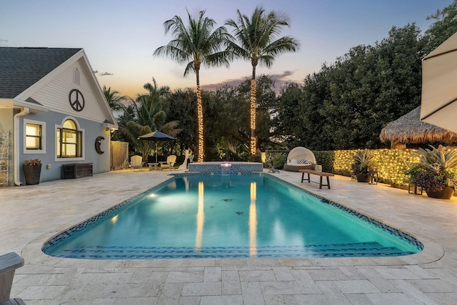 pool at dusk with a patio and cooling unit