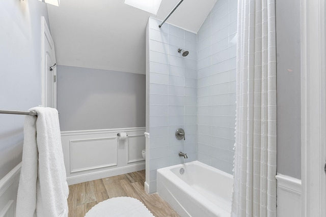 bathroom featuring hardwood / wood-style flooring, vaulted ceiling, shower / bath combination with curtain, and toilet