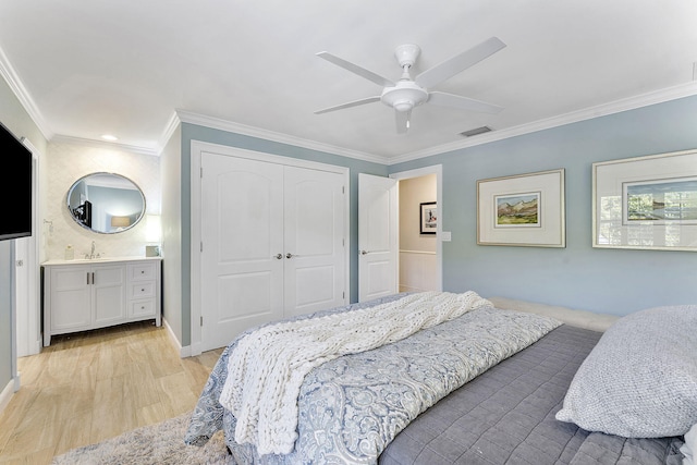 bedroom featuring crown molding, a closet, ensuite bath, and light hardwood / wood-style flooring