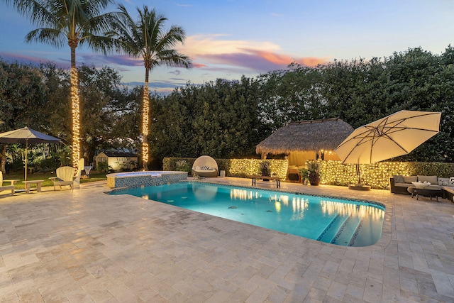 pool at dusk featuring an in ground hot tub, outdoor lounge area, and a patio area