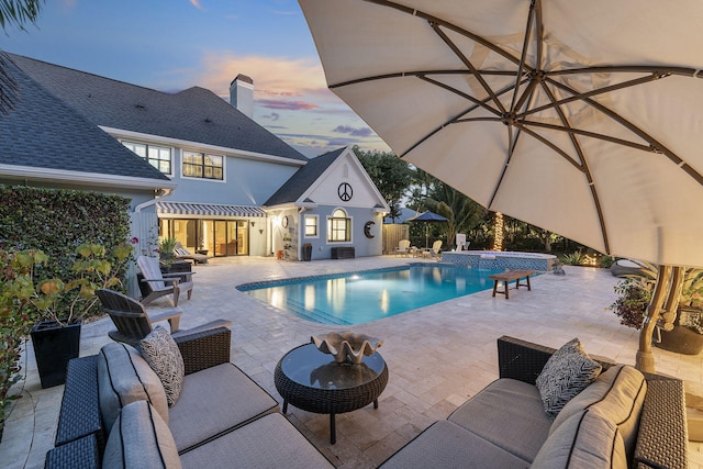 pool at dusk with an outdoor living space, a patio, and an outdoor structure