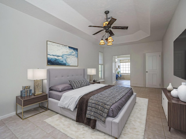 bedroom featuring a raised ceiling, a textured ceiling, and light tile patterned floors