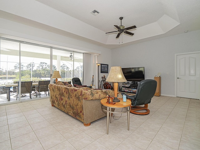 living room with light tile patterned floors, a raised ceiling, and ceiling fan