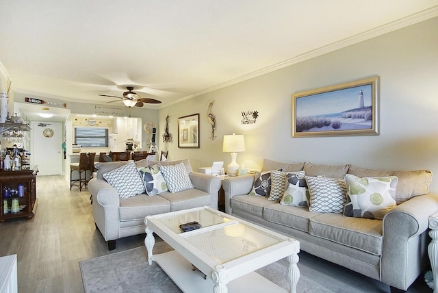 living room with hardwood / wood-style flooring, ornamental molding, and ceiling fan