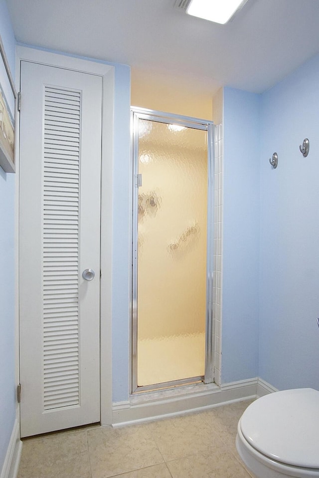 bathroom with tile patterned flooring, a shower with shower door, and toilet