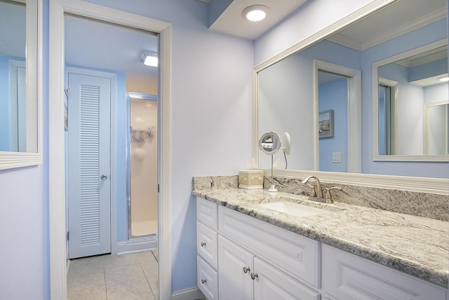 bathroom with tile patterned floors, vanity, a shower with shower door, and ornamental molding