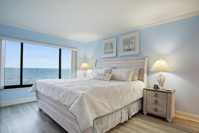 bedroom with crown molding, a water view, and hardwood / wood-style floors