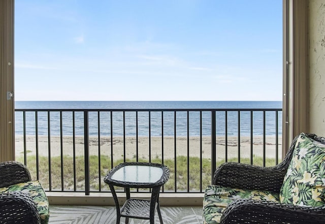 balcony featuring a view of the beach and a water view