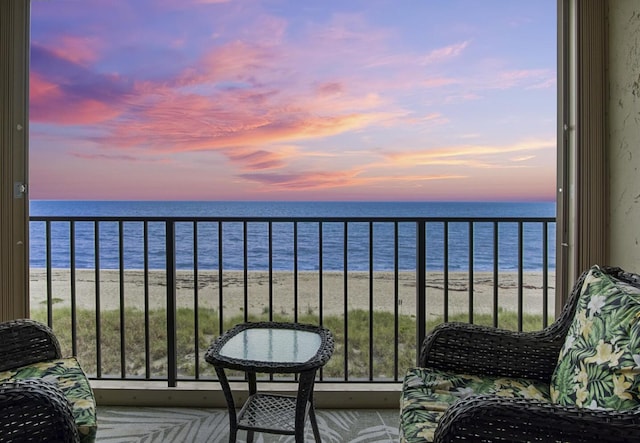 balcony at dusk with a water view and a beach view