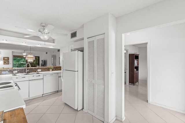 kitchen featuring sink, a textured ceiling, light tile patterned floors, white appliances, and white cabinets