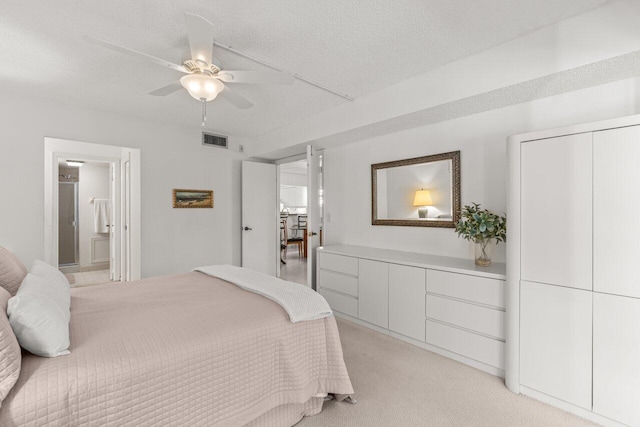 carpeted bedroom with ceiling fan, connected bathroom, and a textured ceiling