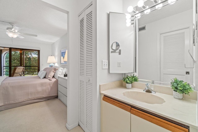 bathroom with vanity, ceiling fan with notable chandelier, and a textured ceiling