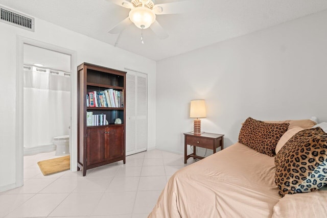 bedroom with ceiling fan, ensuite bathroom, a textured ceiling, and light tile patterned flooring