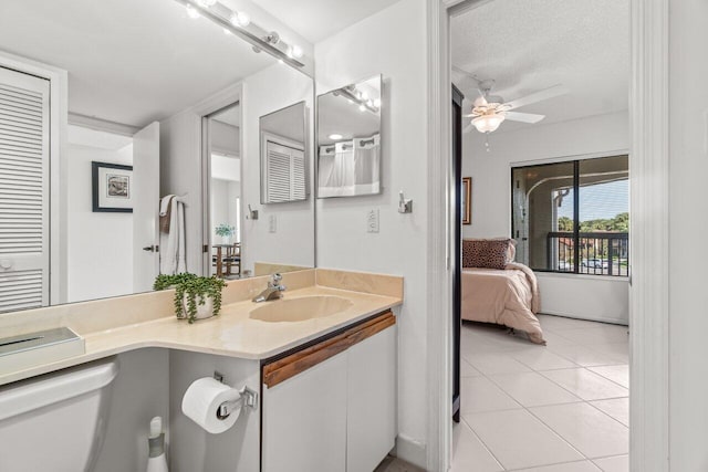 bathroom with toilet, a textured ceiling, vanity, ceiling fan, and tile patterned flooring