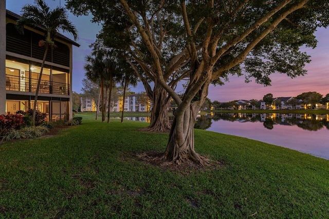 yard at dusk with a water view and a balcony