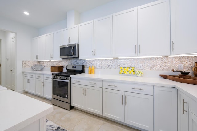 kitchen with light tile patterned floors, decorative backsplash, stainless steel appliances, and white cabinets