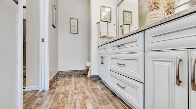 bathroom featuring wood-type flooring, toilet, and vanity