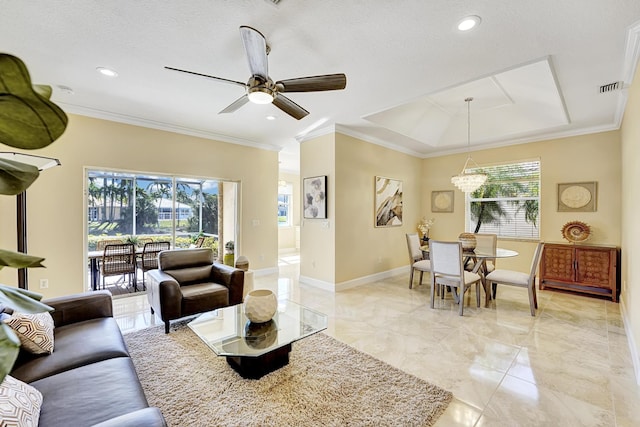 living room with a tray ceiling, ceiling fan with notable chandelier, ornamental molding, and a textured ceiling