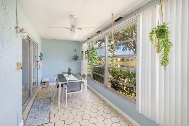 sunroom / solarium featuring ceiling fan and a water view