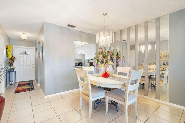 tiled dining room with a notable chandelier and a textured ceiling