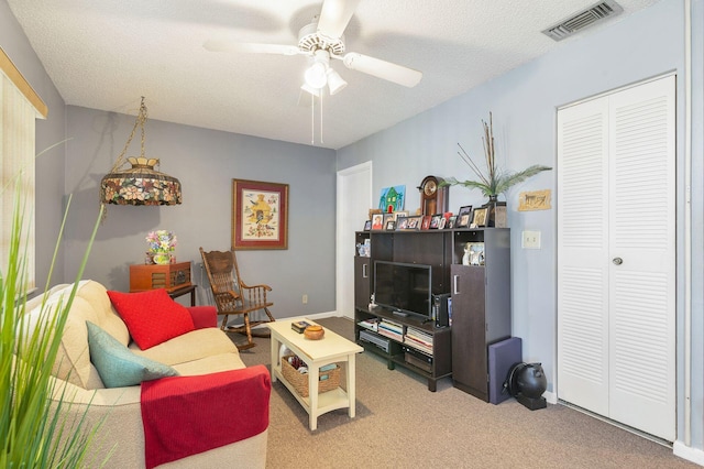 living room with ceiling fan, carpet flooring, and a textured ceiling