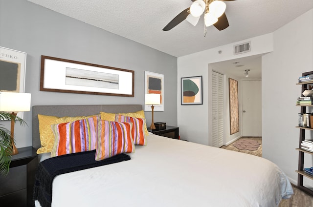 bedroom with ceiling fan, a textured ceiling, and light wood-type flooring