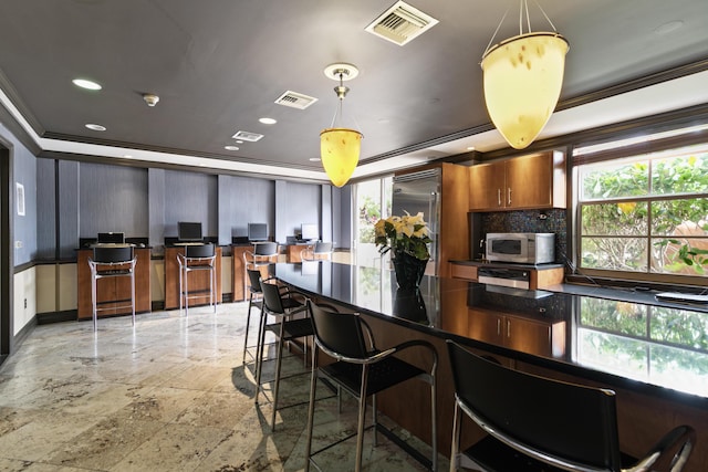 kitchen with crown molding, stainless steel appliances, tasteful backsplash, a kitchen bar, and decorative light fixtures