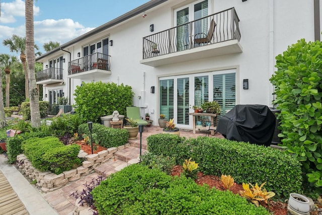 rear view of property featuring a balcony, central AC unit, and a patio