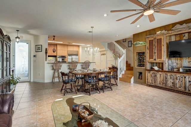 tiled dining room featuring ceiling fan with notable chandelier