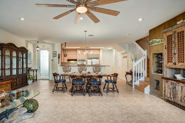 dining space featuring light tile patterned flooring and ceiling fan with notable chandelier