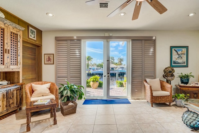 sitting room with light tile patterned floors, ceiling fan, and a water view