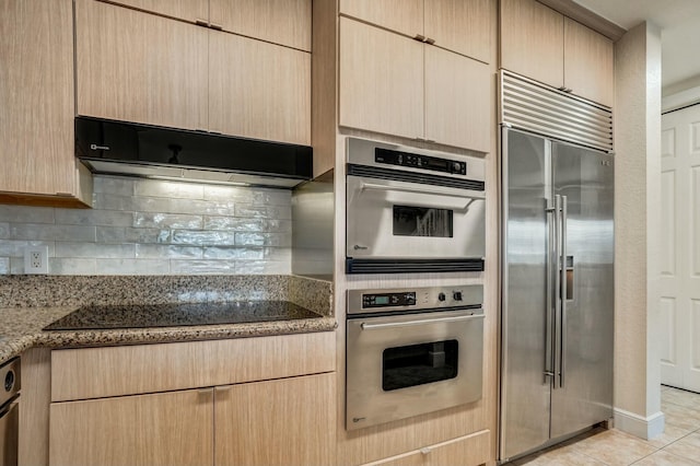 kitchen with tasteful backsplash, appliances with stainless steel finishes, light brown cabinets, and dark stone counters