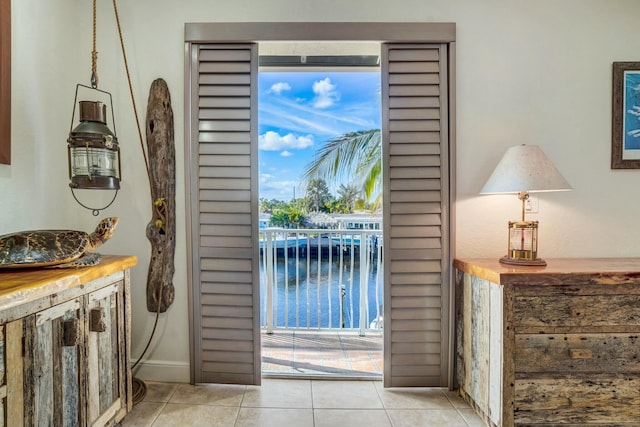 doorway featuring a water view and light tile patterned floors