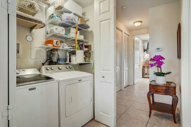 clothes washing area featuring light tile patterned floors and washing machine and clothes dryer