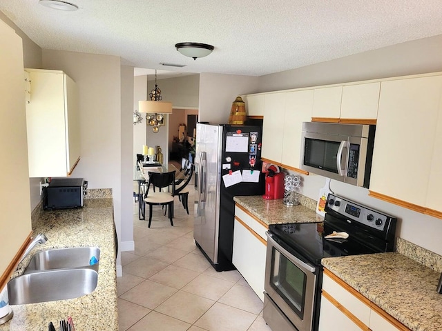 kitchen with sink, white cabinetry, a textured ceiling, light tile patterned floors, and appliances with stainless steel finishes