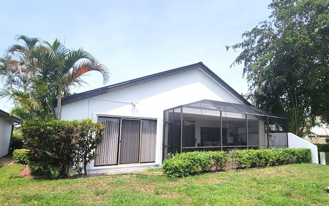 back of house featuring a lanai and a lawn