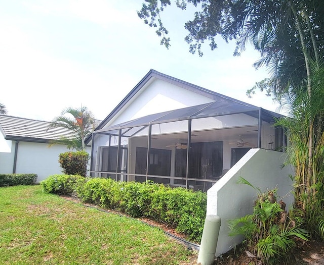 back of property featuring a yard, ceiling fan, and glass enclosure