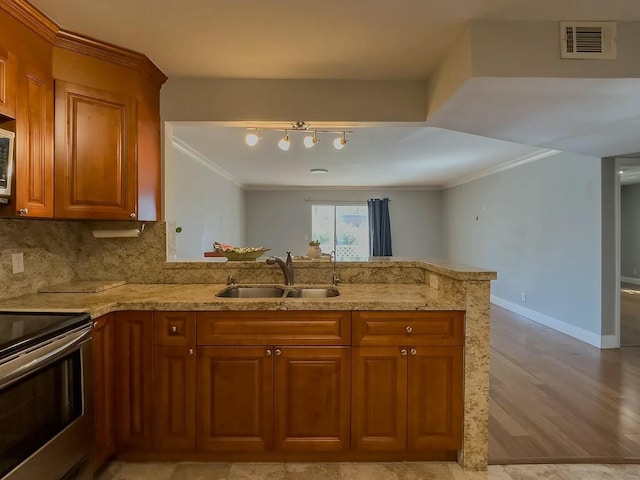 kitchen featuring sink, ornamental molding, appliances with stainless steel finishes, kitchen peninsula, and backsplash