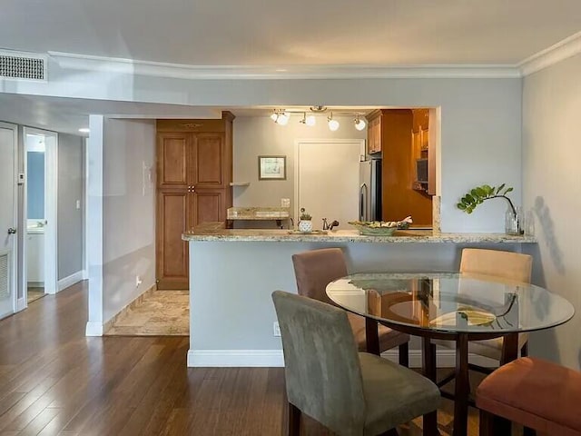 dining area with dark wood-type flooring and crown molding