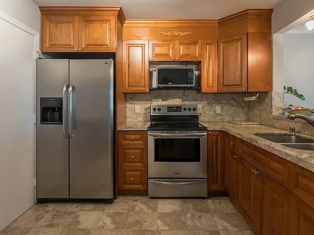 kitchen featuring light stone counters, sink, backsplash, and stainless steel appliances