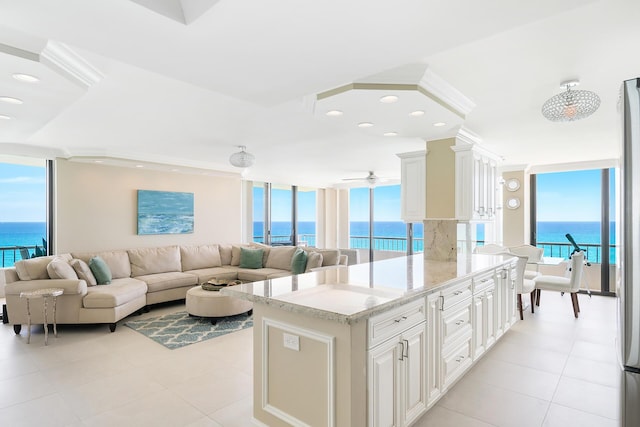 interior space with white cabinetry, light stone countertops, a healthy amount of sunlight, and a water view