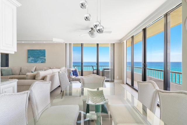 living room with a wall of windows, ceiling fan, and a water view