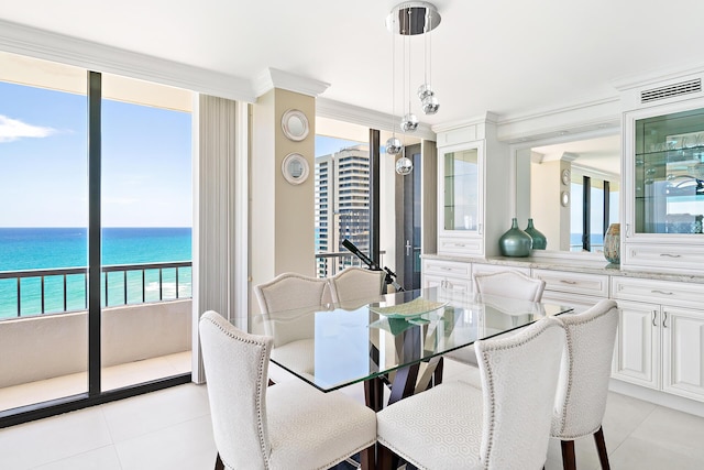 dining space featuring light tile patterned flooring, a water view, and ornamental molding